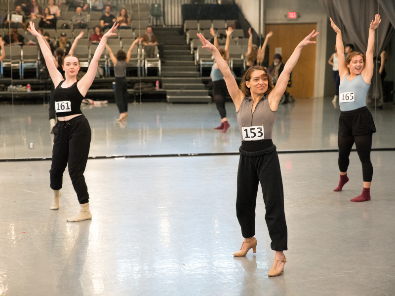 three dancers smiling with their arms up in a pose during a dance audition